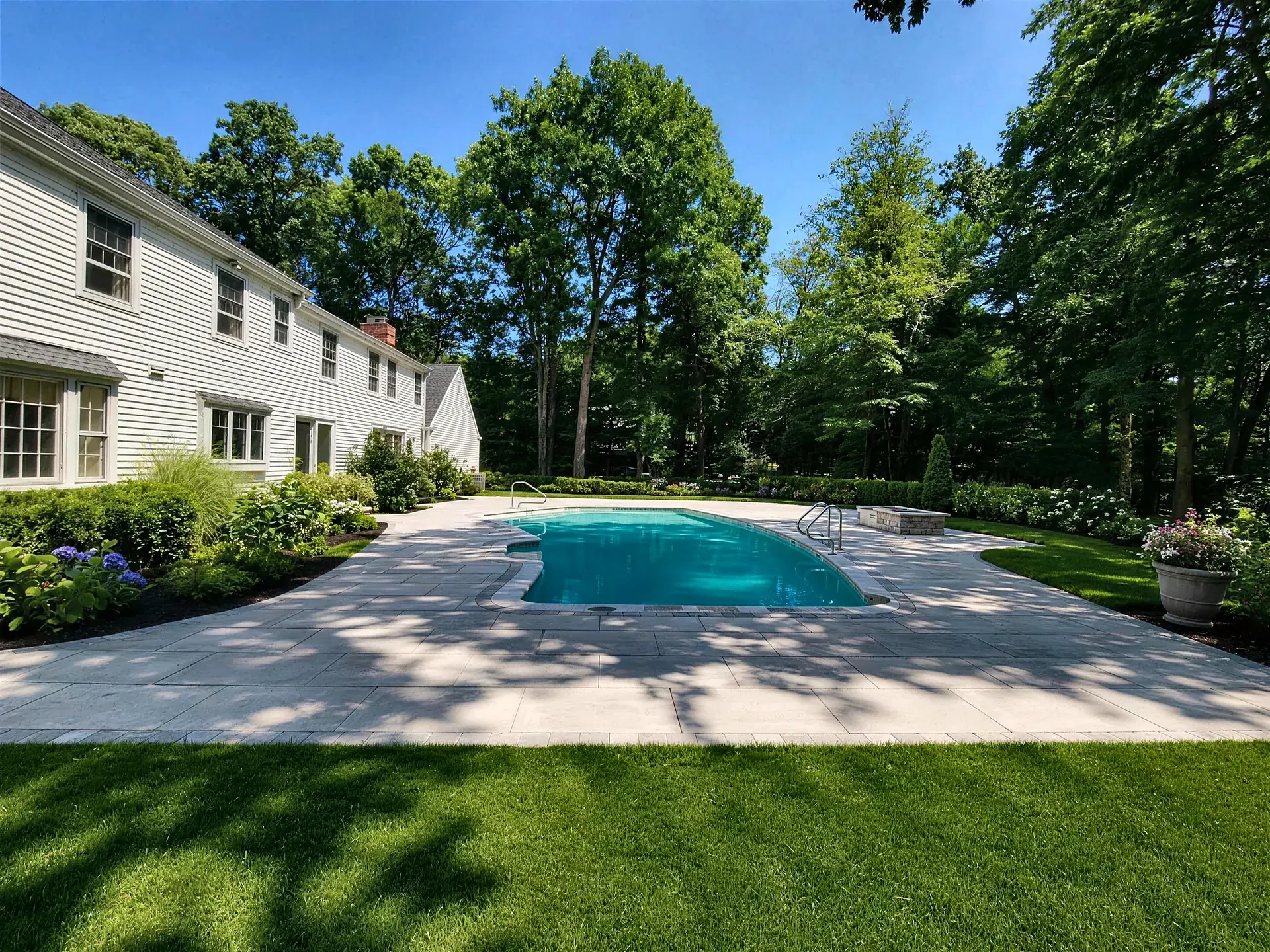 Free-form pool with a wide paver deck and lawn in Lynnfield, MA
