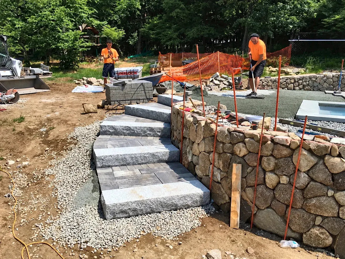 Granite steps being set through a round-fieldstone retaining wall in North Reading, MA, built by Gerrior