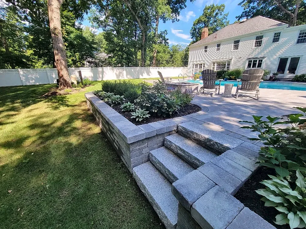 Granite steps beside a raised planting bed at a pool patio in Lynnfield, MA
