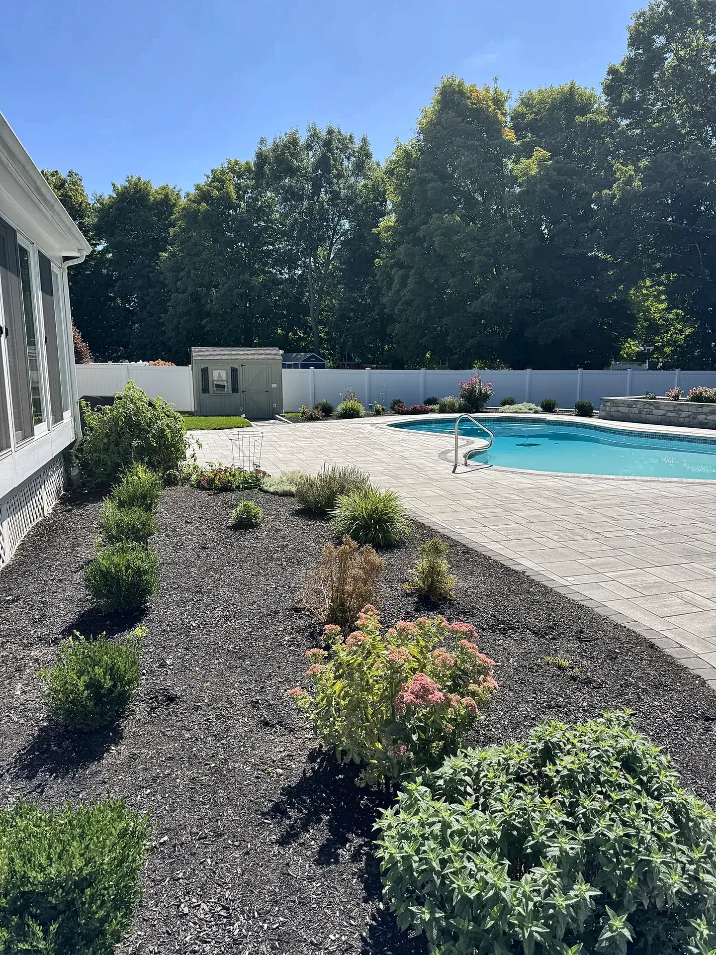 Paver pool deck edged by new planting beds in Reading, MA