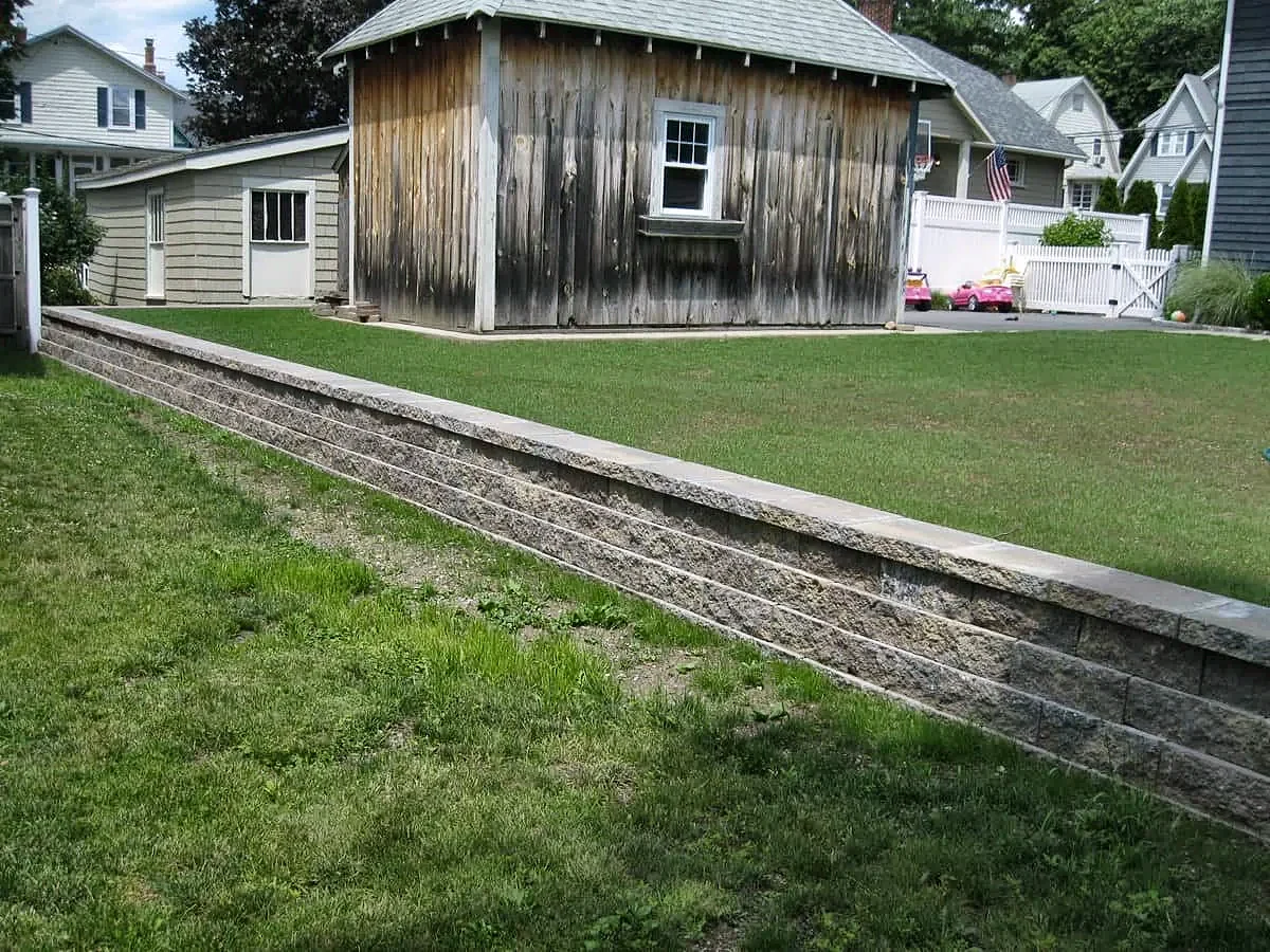 Segmental block retaining wall with a cap along a lawn next to a shed