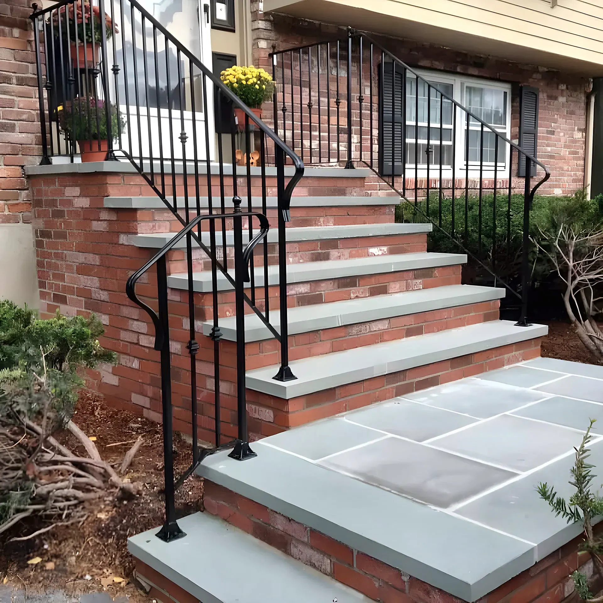 Red brick front steps with blue-gray stone treads and a blue-gray stone landing, with black iron railings