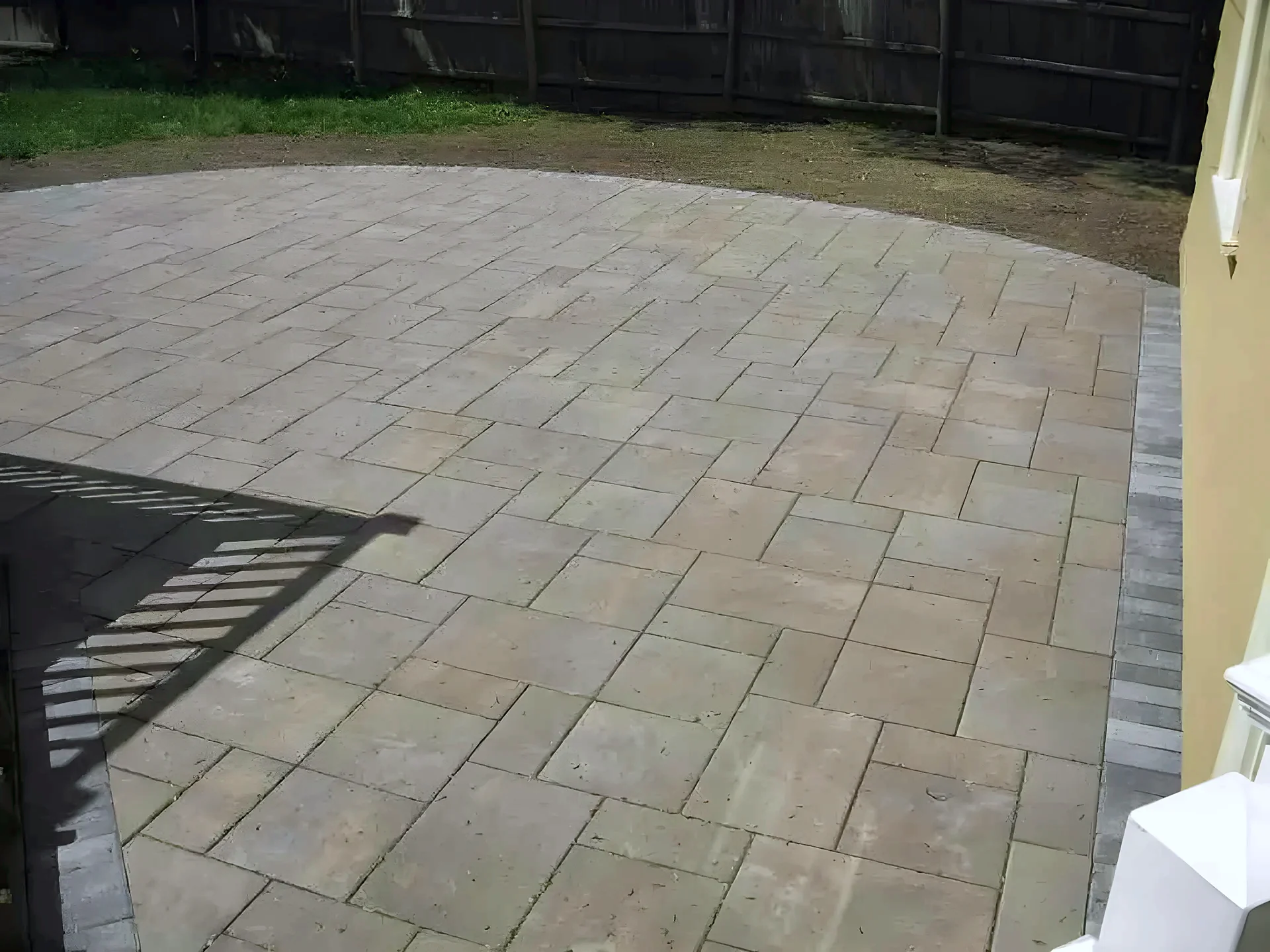 Tan rectangular paver patio with a dark border row beside a house